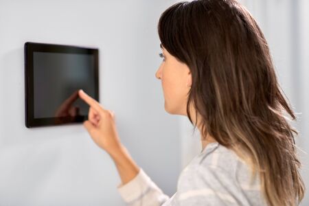 automation, internet of things and technology concept - woman using tablet pc computer at smart homeの写真素材