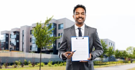 indian man realtor with contract on city street