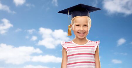 happy girl in bachelor hat or mortarboard over skyの写真素材