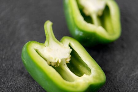 cut green pepper on slate stone background