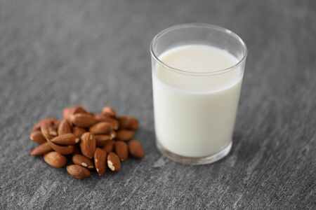 glass of lactose free milk and almonds on tableの写真素材