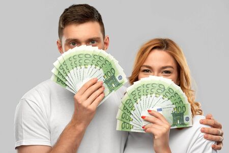 finance, saving and people concept - portrait of happy couple in white t-shirts with euro money over...