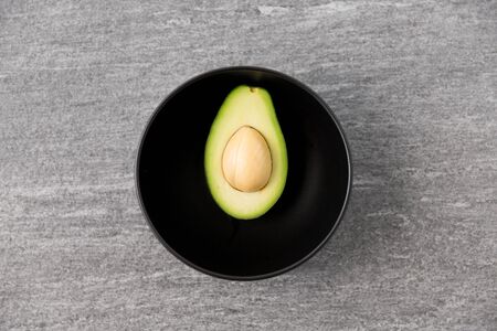 close up of ripe avocado with bone in ceramic bowlの写真素材