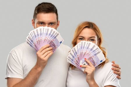 happy couple in white t-shirts with euro moneyの写真素材