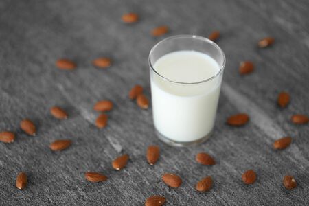 glass of lactose free milk and almonds on tableの写真素材
