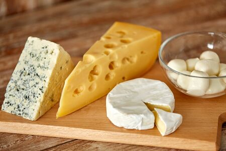 different kinds of cheese on wooden cutting boardの写真素材