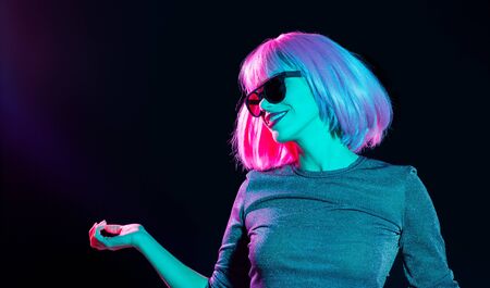 happy woman in pink wig and sunglasses dancingの写真素材