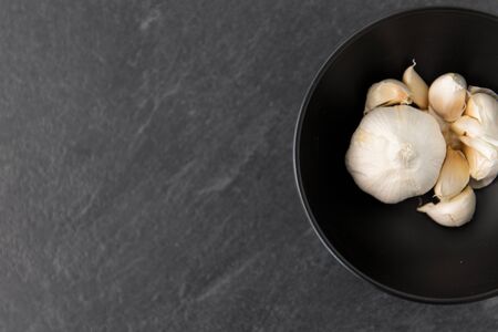 garlic in bowl on slate stone backgroundの写真素材