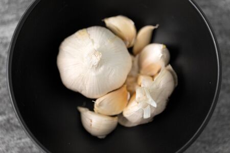 vegetable, food and culinary concept - garlic in bowl on slate stone backgroundの写真素材