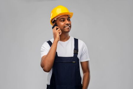 indian builder in helmet calling on smartphone