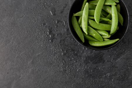 Peas in bowl on wet slate stoneの写真素材