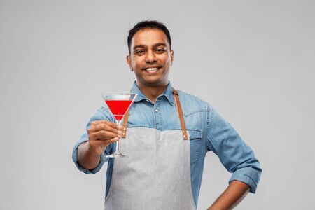 Indian barman in apron with glass of cocktailの写真素材