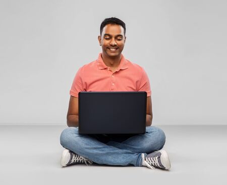 Happy indian man with laptop computer on floorの写真素材