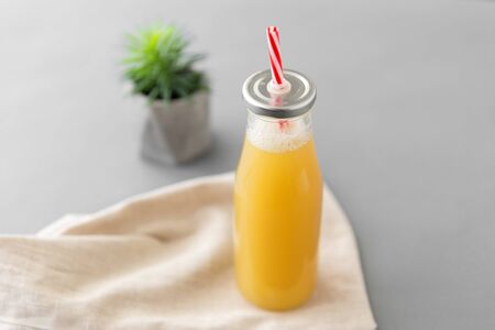 healthy eating, dieting and eco friendly concept - reusable glass bottle of fruit juice with straw