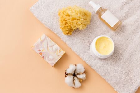 beauty, spa and wellness concept - close up of crafted soap bar, body butter, natural sponge and essential oil on bath towelの写真素材