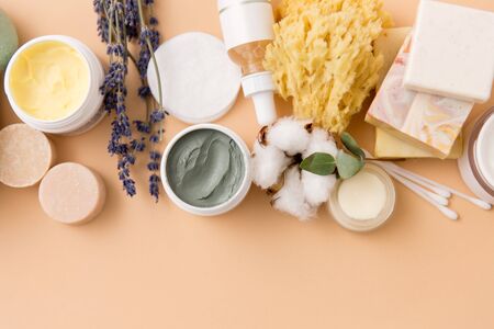 beauty, spa and wellness concept - close up of crafted soap bars, natural bristle wooden brush, body butter with sponge and herbs on beige backgroundの写真素材