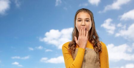 emotion, expression and people concept - scared or yawning teenage girl closing her mouth by hand...