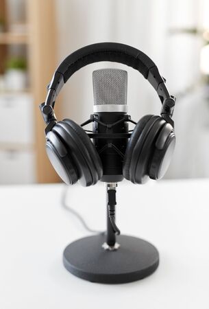 technology and audio equipment concept - headphones and microphone at home office or recording studioの写真素材