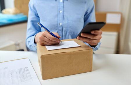 delivery, mail service, people and shipment concept - close up of woman filling postal form at officeの写真素材