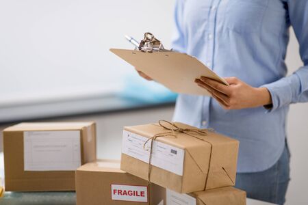 delivery, mail service, people and shipment concept - close up of woman with parcel boxes and...