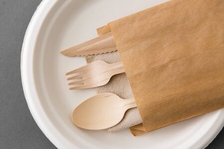 cutlery, recycling and eco friendly concept - set of wooden spoon, fork and knife on paper plate on...