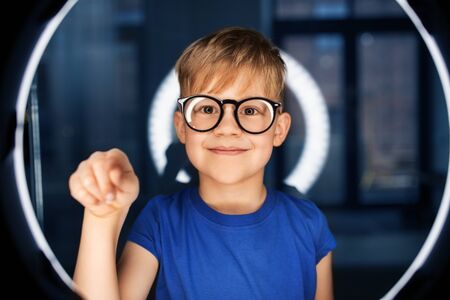 boy in glasses over illumination in dark room