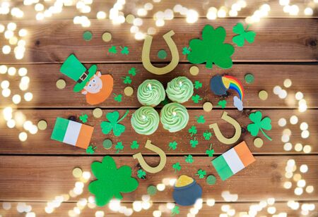 st patricks day, holidays and celebration concept - green cupcakes with candles, horseshoes and...