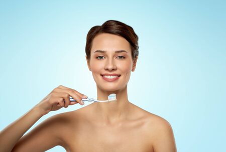 smiling woman with toothbrush cleaning teeth