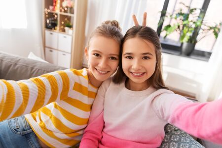 happy teenage girls taking selfie at home