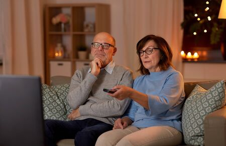 senior couple watching tv at home in evening