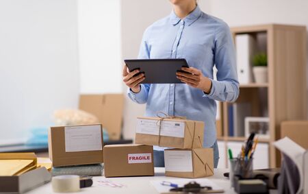 woman with tablet pc and parcels at post office