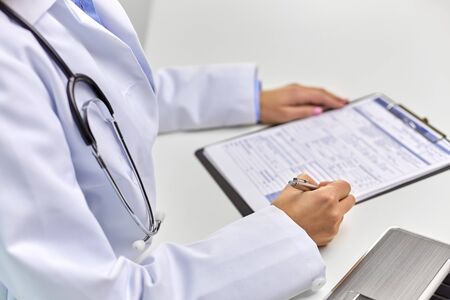 medicine, healthcare and people concept - close up of female doctor writing medical report