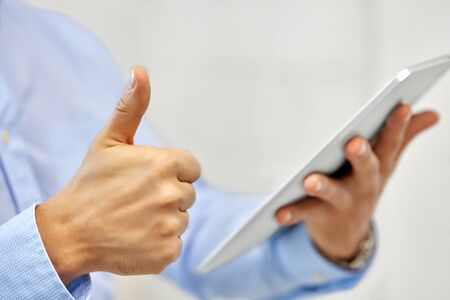 business, people and technology concept - close up of male hands with tablet pc computer showing thumbs upの写真素材