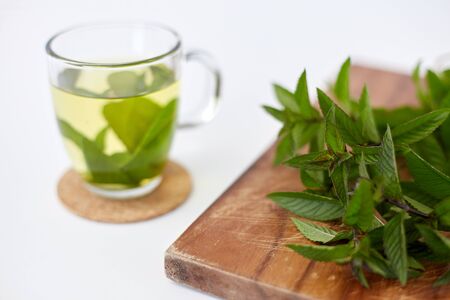 drinks, herbs and ethnoscience concept - herbal tea with fresh peppermint on wooden boardの写真素材