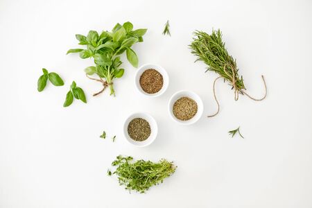 greens, culinary and flavoring concept - fresh basil, rosemary and thyme with dry seasoning in cups on white backgroundの写真素材