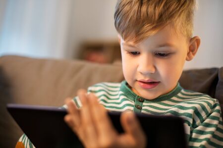 childhood, technology and people concept - happy little boy with tablet pc computer at home
