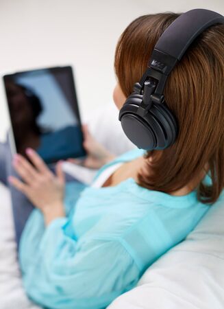 woman with tablet pc and headphones at homeの写真素材