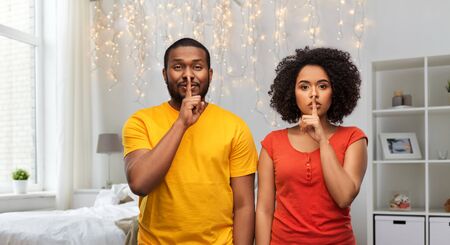 happy african american couple making hush gesture