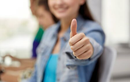 close up of happy student girl showing thumbs upの写真素材