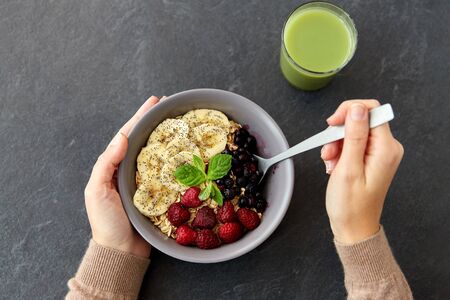 hands of woman eating cereal breakfast with spoonの写真素材