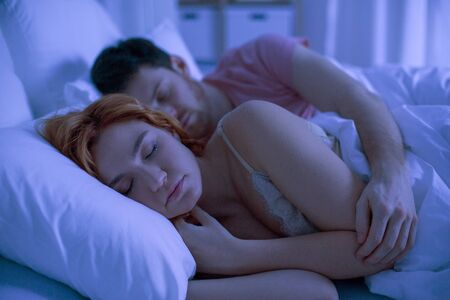 happy couple sleeping in bed at homeの写真素材