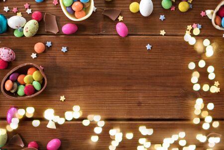 easter, sweets and confectionery concept - chocolate eggs and candy drops on wooden backgroundの写真素材