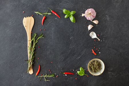 food, culinary and eating concept - rosemary, garlic, thyme and red chili pepper on stone surfaceの写真素材