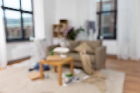 mess, disorder and interior concept - blurred photo of messy home living room with scattered stuffの写真素材
