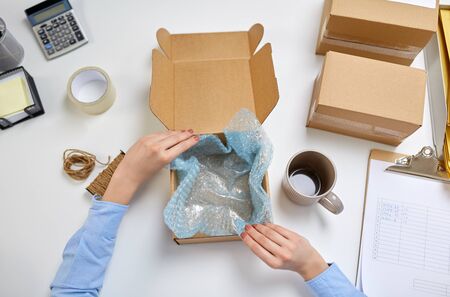 hands packing mug to parcel box at post office