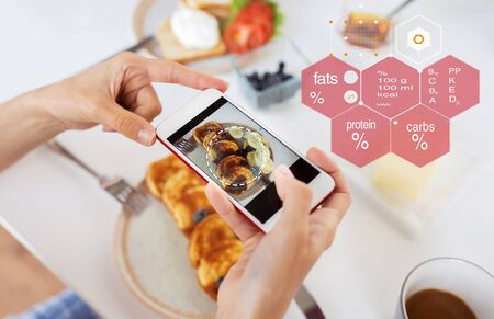 food , eating and technology concept - hands with pancakes on smartphone screen over nutritional...