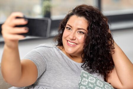 happy woman taking selfie with smartphone at home