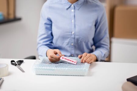 woman sticking fragile mark to wrap at post office