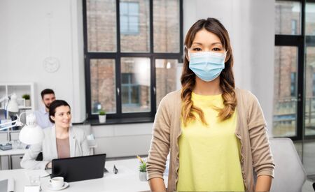 asian woman in protective medical mask at officeの写真素材