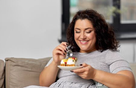 smiling young woman eating cake at homeの写真素材